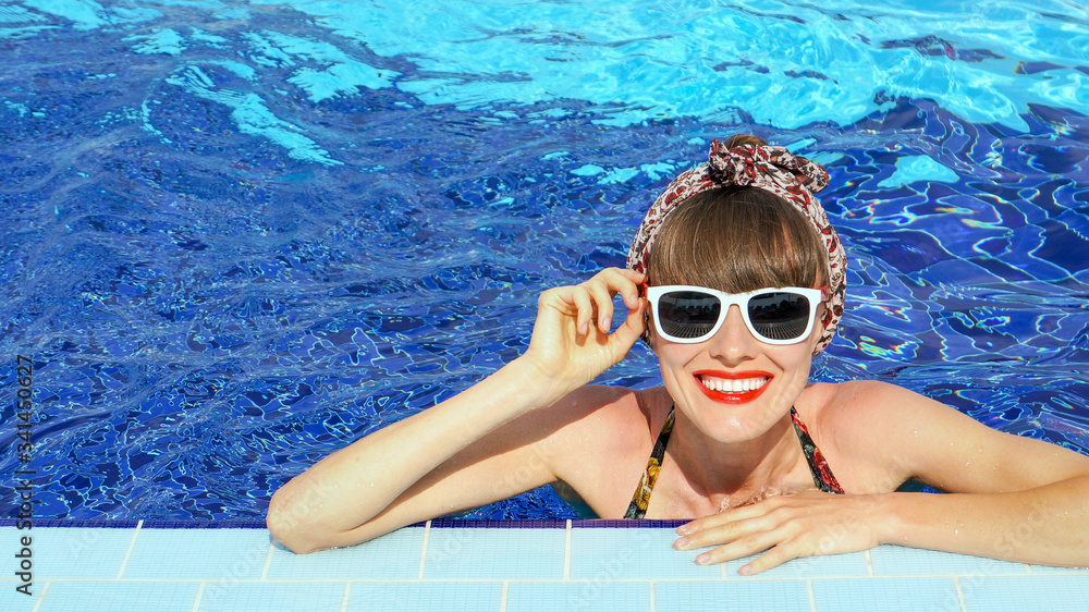 Stylish portrait of pretty young woman posing in the swimming pool.  Swimsuit, sunglasses, retro look, outdoor fashion portrait elegant woman relaxing