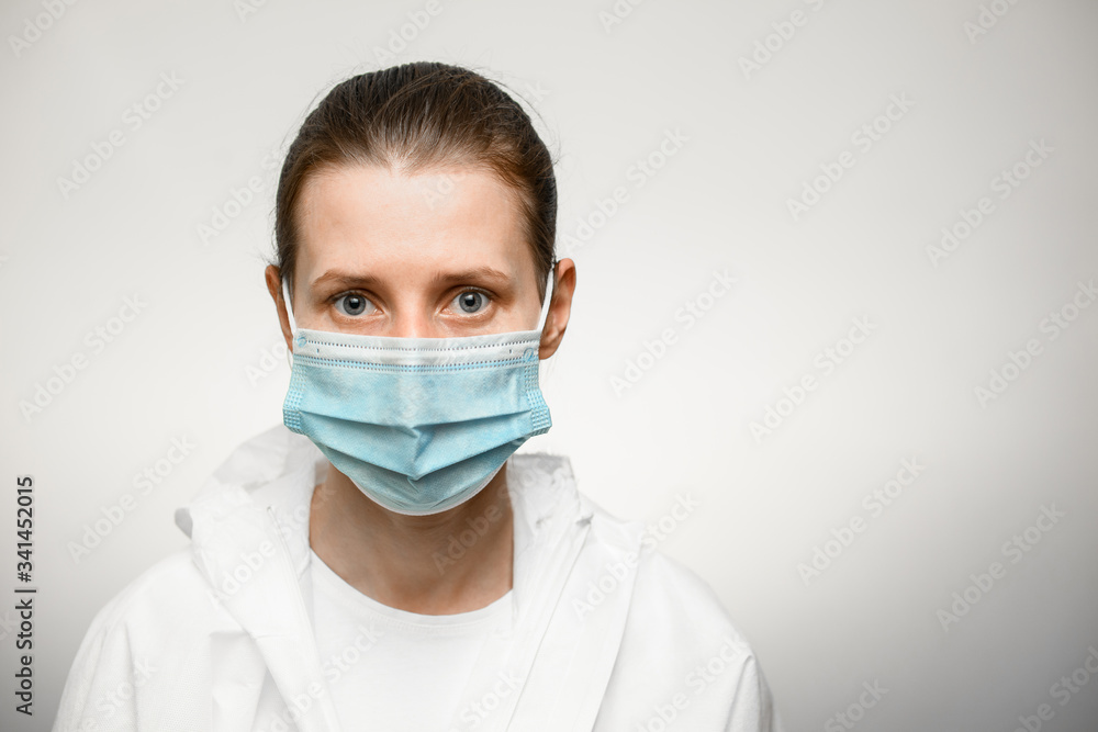 woman in medical mask and white protective suit looks at camera. woman in medical mask and white protective suit looks at camera.