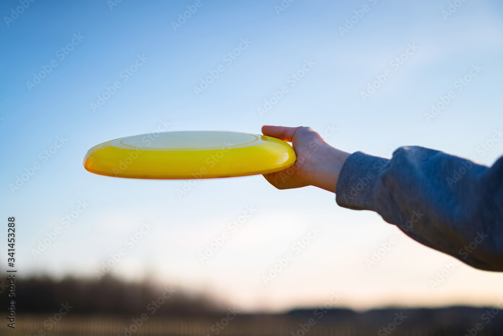 Hand holding yellow frisbee outside. Flaying frisbee outdoors with blue sky  in the background Stock Photo | Adobe Stock