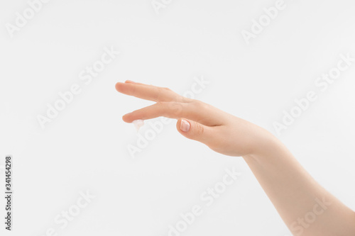 Skincare, hydration of woman's hand by droplet of cream on grey background. Beautiful woman hand with cream. Palm facing down.