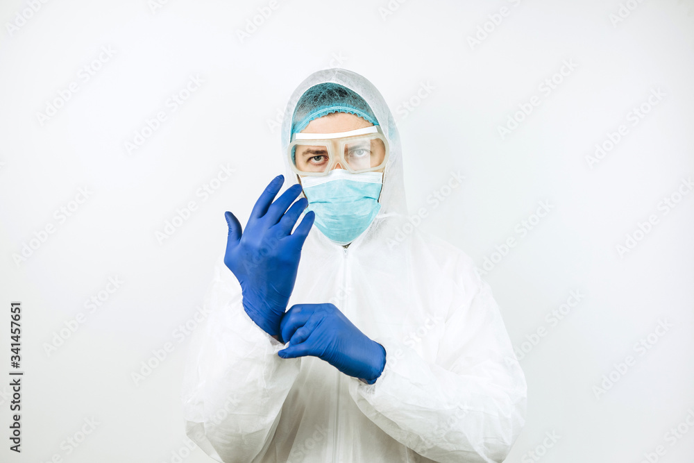 portrait of tired doctor after shift in the hospital. The doctor in protective clothing - glasses, mask, gloves on white background. The doctor treating patients with coronavirus. Covid-2019 portrait of tired doctor after shift in the hospital. The doctor in protective clothing - glasses, mask, gloves on white background. The doctor treating patients with coronavirus. Covid-2019