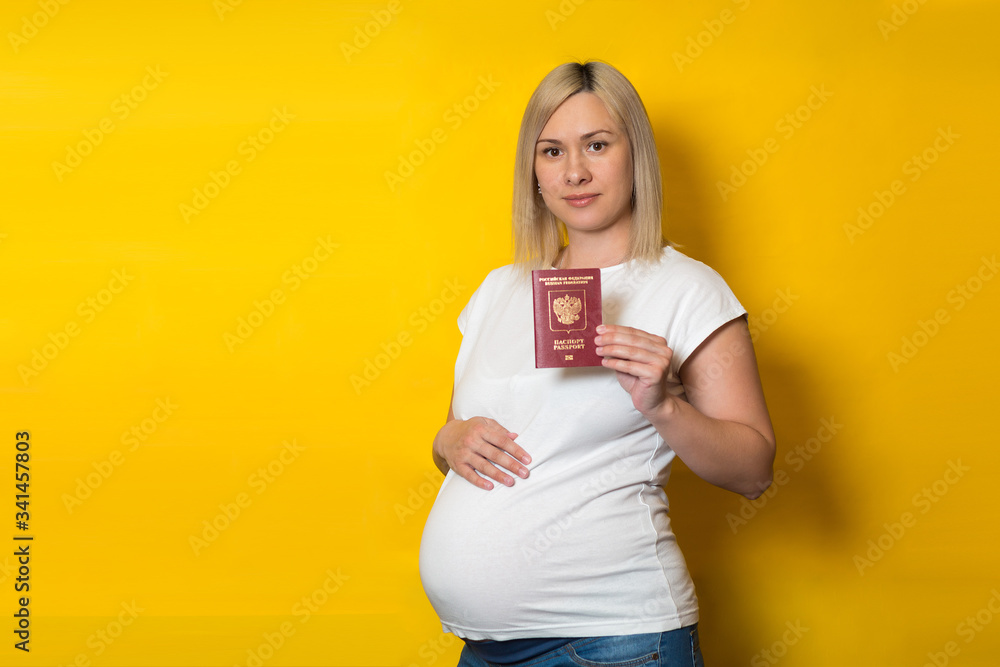 happy pregnant woman with passport on a yellow background. Benefits for pregnant women. registration of allowances happy pregnant woman with passport on a yellow background. Benefits for pregnant women. registration of allowances