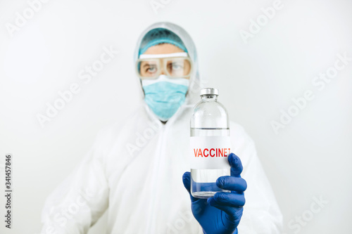 A doctor in a white coat and blue gloves holds a syringe test tube with a coronavirus vaccine. Covid 2019 vaccine injection. 2020 pandemic coronavirus. Vaccine test.