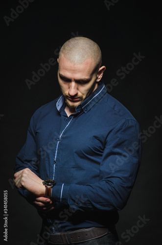 A stylish, bald young man stands on a dark background in the category. Business, Finance