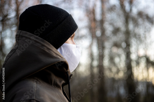 Close-up of a young man in the woods with a face mask from the side © PatriksPauls