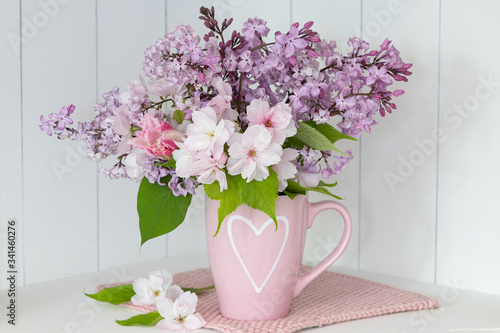 Blumenstrauß mit Flieder und Zierapfel in Tasse mit Herzmotiv