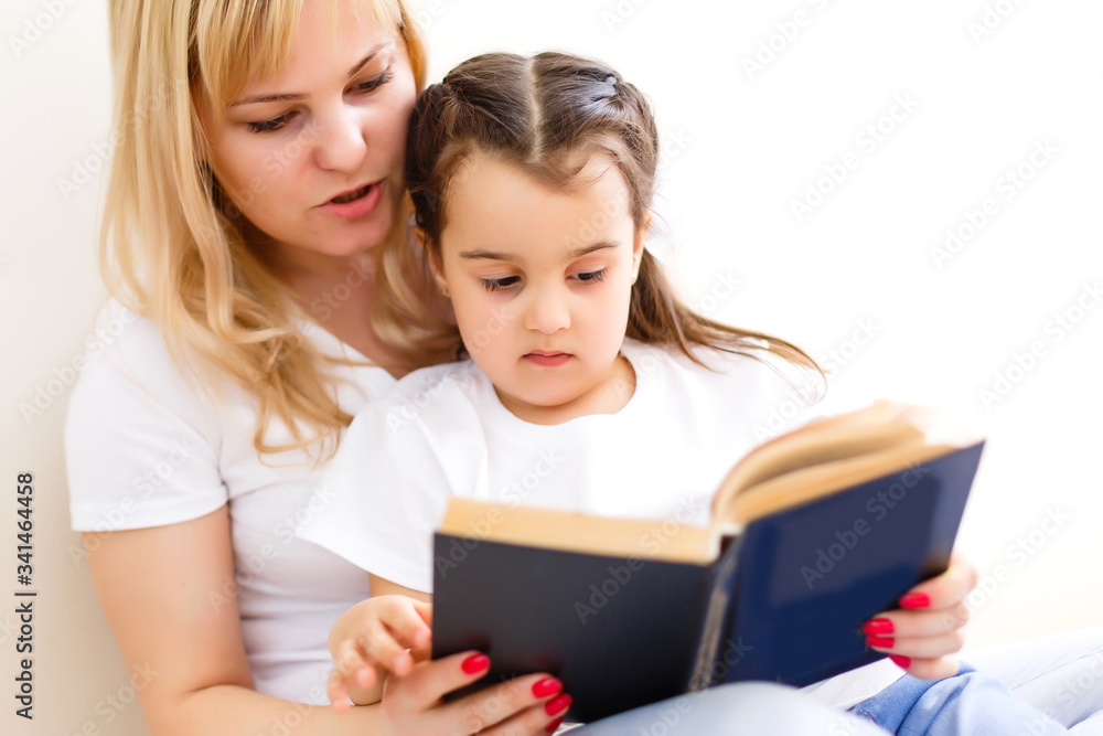 Mother And Daughter Reading Story At Home Together