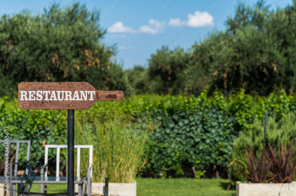 Arrow sign saying restaurant against the background of green trees. Concept of restaurant and hospitality business. Arrow sign saying restaurant against the background of green trees. Concept of restaurant and hospitality business.