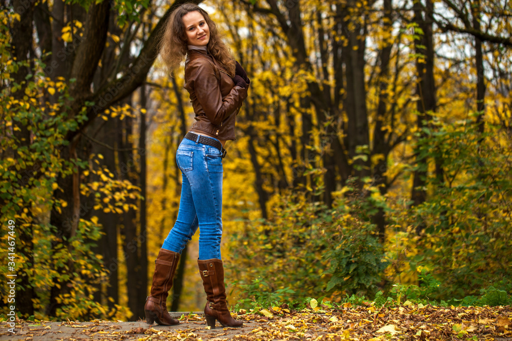 Full body portrait of a young beautiful woman in blue jeans in autumn park Full body portrait of a young beautiful woman in blue jeans in autumn park