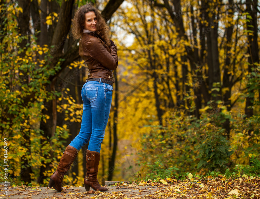 Full body portrait of a young beautiful woman in blue jeans in autumn park Full body portrait of a young beautiful woman in blue jeans in autumn park