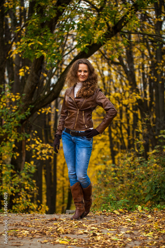 Full body portrait of a young beautiful woman in blue jeans in autumn park