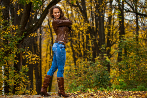 Full body portrait of a young beautiful woman in blue jeans in autumn park