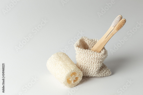 two toothbrushes made of natural wood and natural loofah in an ecological bag. zero waste. on a gray background