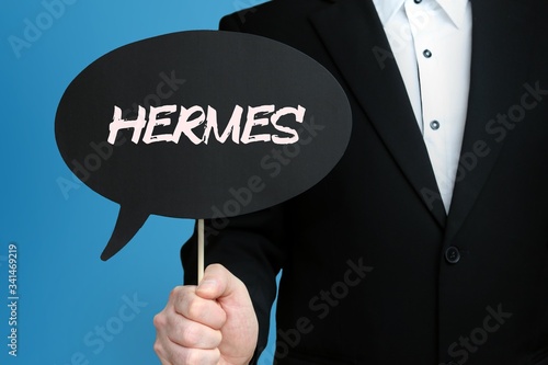 HERMES. Geschäftsmann im Anzug hält Sprechblase in die Kamera. Der Begriff HERMES steht im Schild. Symbol für Business, Finanzen, Statistik, Analyse, Wirtschaft