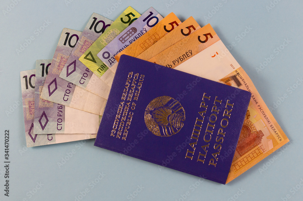 Fototapeta premium Belarusian passport and new banknotes in the Republic of Belarus with a face value of one hundred fifty five rubles. Separate on a blue background.