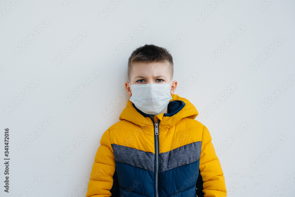 A boy stands on a gray background in a mask during a quarantine with free space. Quarantine in the mask A boy stands on a gray background in a mask during a quarantine with free space. Quarantine in the mask