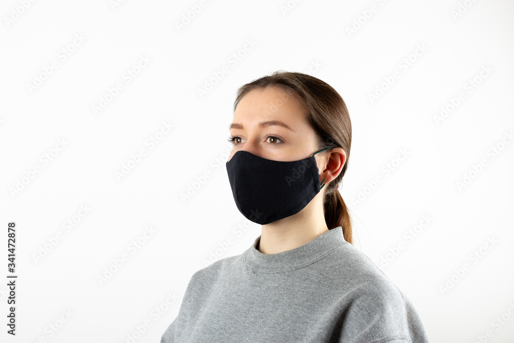 Portrait of young woman wearing black face mask isolated on gray background. Dust protection against virus. Coronavirus pandemic time. Female looking at camera Portrait of young woman wearing black face mask isolated on gray background. Dust protection against virus. Coronavirus pandemic time. Female looking at camera