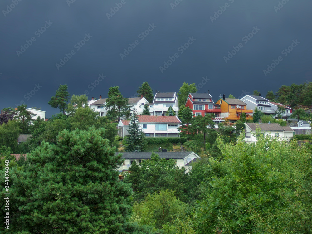 A small modern mountain village surrounded by a dense mixed forest in the background of clouds before the rain. Family and pensioners trips to mountain scenic places. A small modern mountain village surrounded by a dense mixed forest in the background of clouds before the rain. Family and pensioners trips to mountain scenic places.
