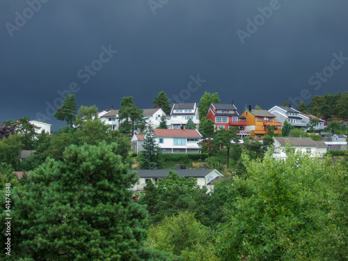 A small modern mountain village surrounded by a dense mixed forest in the background of clouds before the rain. Family and pensioners trips to mountain scenic places.