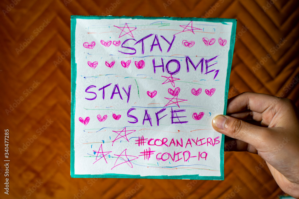 Stay home stay safe coronavirus covid-19 poster message in the hand of female Stay home stay safe coronavirus covid-19 poster message in the hand of female
