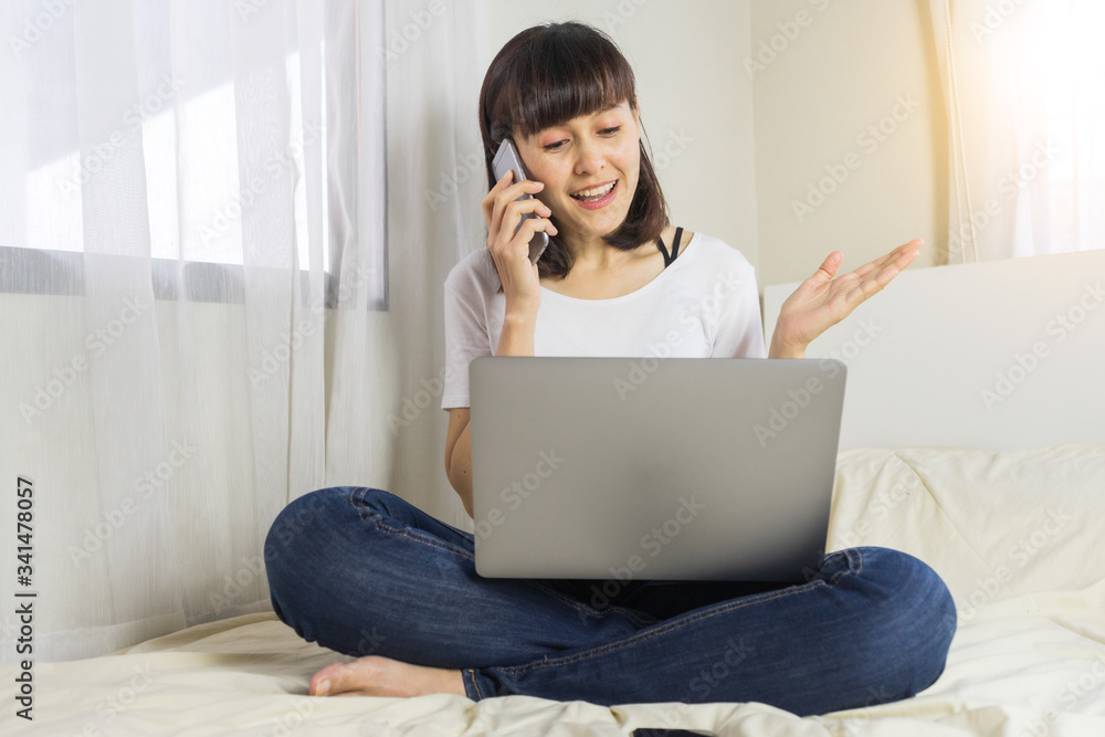 Asian woman working on laptop and smartphone in bed. Work from home, Relaxing working process. Asian woman working on laptop and smartphone in bed. Work from home, Relaxing working process.