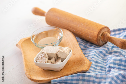 dried and fresh yeast on a white kitchen bacground with wooden rolling pin