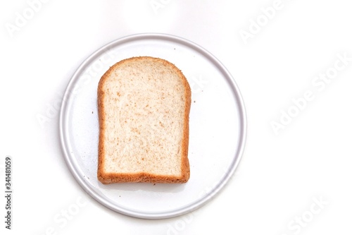 A piece of sliced wholewheat bread on a white plate, white isolated background 