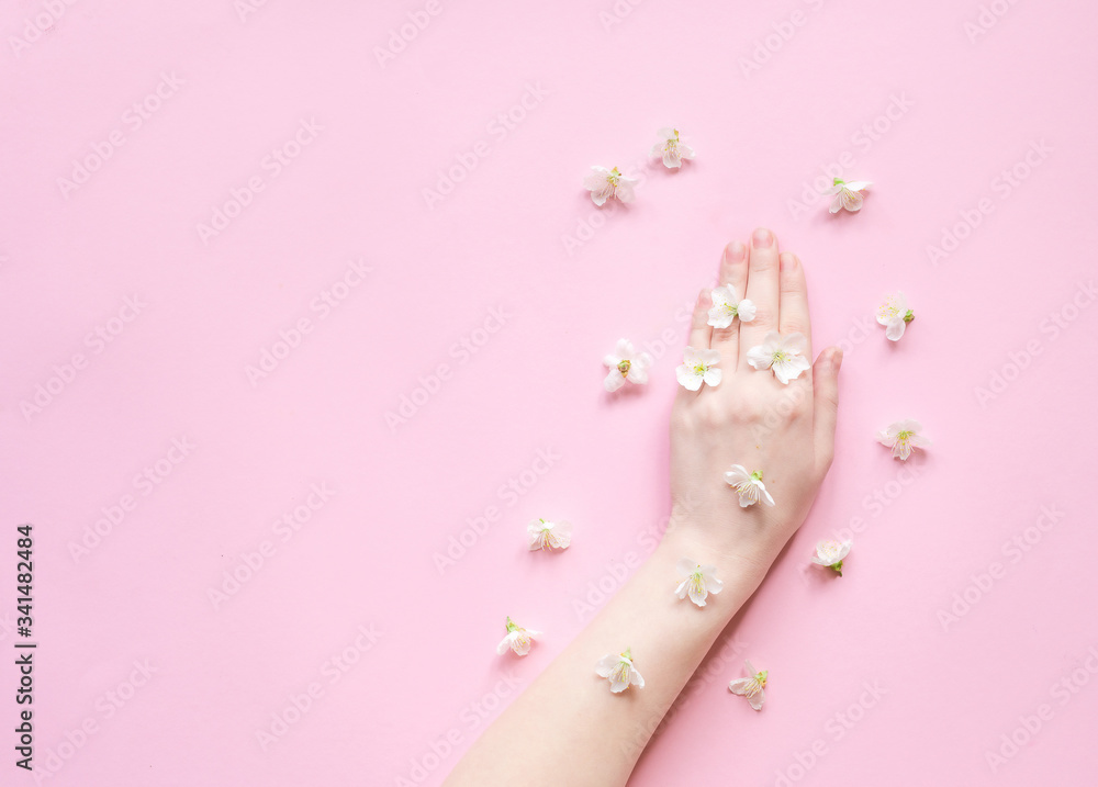 Hands of a woman with white flowers on a pink background. Natural cosmetics product and hand care, moisturizing and wrinkle reduction. Flat Lay and skincare concept.