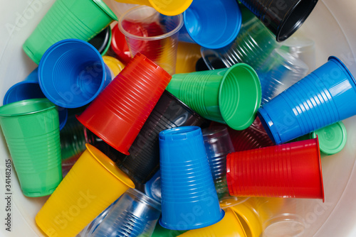 A large pile of multicolored plastic cups scattered on the floor. Pollution of the environment by human waste