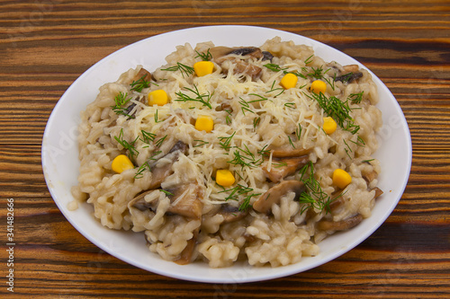 Tasty appetizing risotto on white plate on wooden table