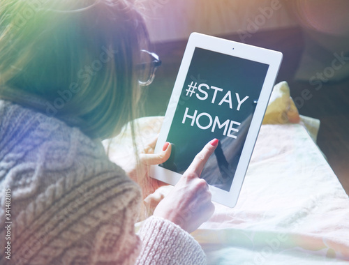 woman lying in bed with digital tablet touching with finger in morning sunlight photo