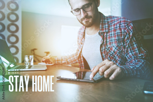 concentrated man with digital tablet, laptop and pen at table photo