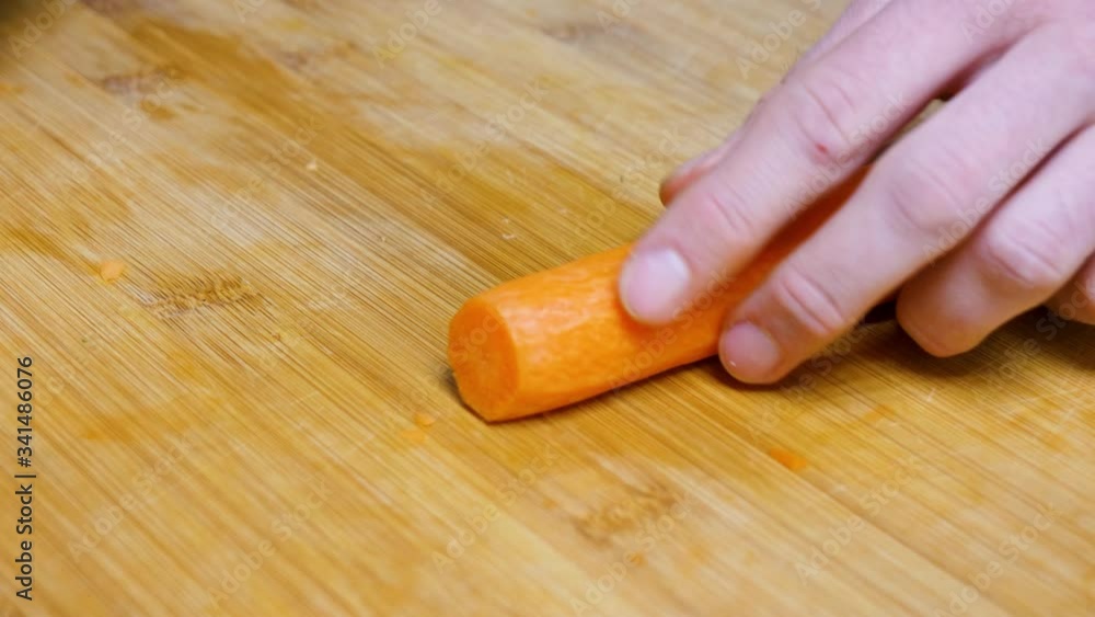 The man chops the carrot. Close shot of a carrot. The man chops the carrot. Close shot of a carrot.