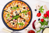 Tasty pizza with salami, mozzarella, mushrooms and olives on wooden background.