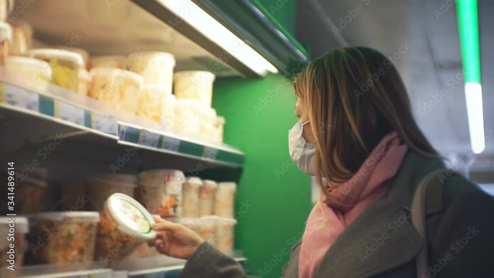 A woman in a medical mask chooses canned vegetables. A woman in a medical mask chooses canned vegetables.