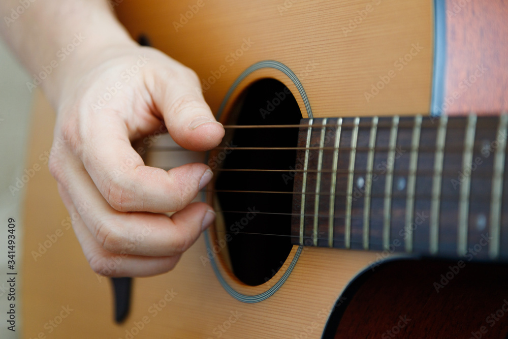 Fototapeta premium Close-up of a male hand playing a guitar. Learning music. Fun, live music.
