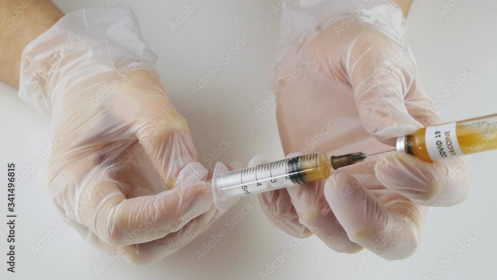 Pours out of the syringe into the vial of yellowish liquid.Vaccine virus nCoV. Pours out of the syringe into the vial of yellowish liquid.Vaccine virus nCoV.