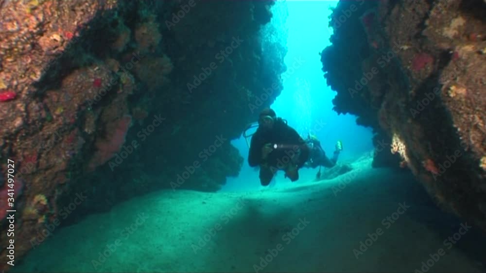 scuba diver underwater exploring the reefs and rocks underwater tunnels ...