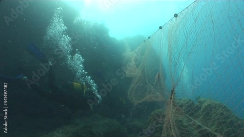 scuba divers around old ghost fhish net underwater dangerous ocean scenery photo