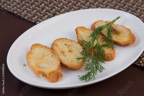 Fried baguette with a crust grated with garlic and salt, decorated with a sprig of dill