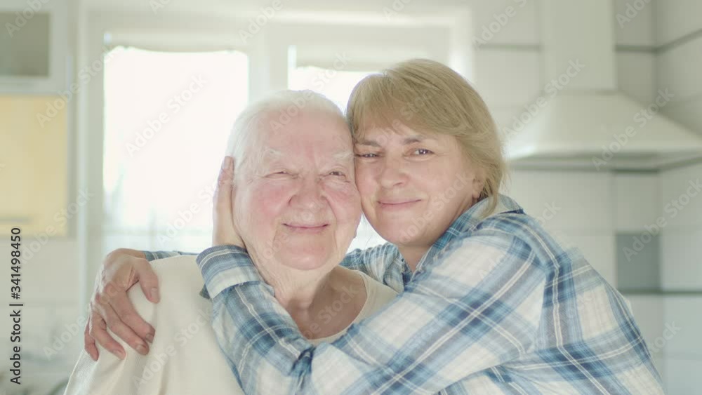 Portrait Of Two Women. Daughter Hugs Her Old Mom. Women In The Kitchen. Portrait Of Two Women. Daughter Hugs Her Old Mom. Women In The Kitchen.
