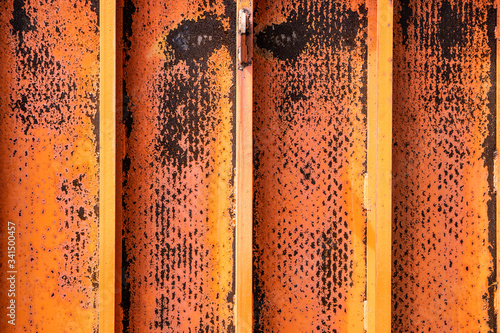 Rusted yellow and orange faded paint over metal textured sheets welded together