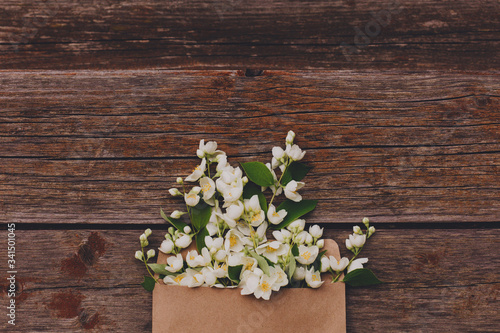 Jasmine flowers in an envelope on a wooden background.