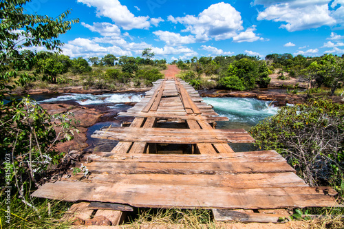 Old and worn out wooden bridge over soninho river in Jalapao, Brazil. Crystal clear water, blue sky. photo