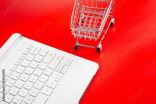 Empty Groceries trolley with keyboard on red background-Online Shopping Concept