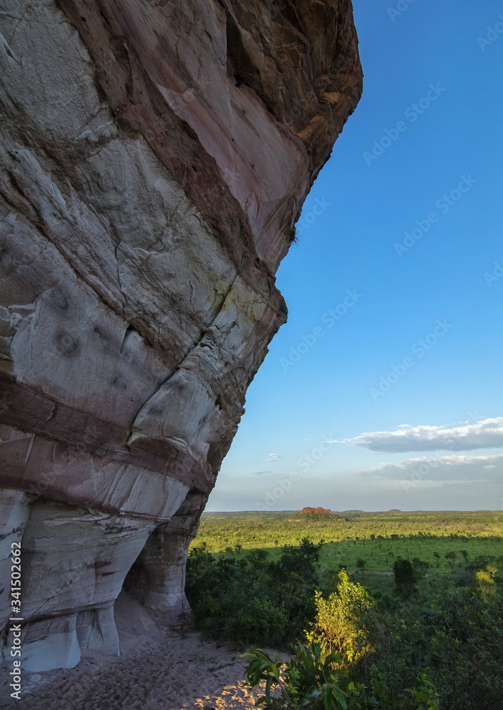 Colorful arenite rock wall, contrasting with green vegetations and blue ...