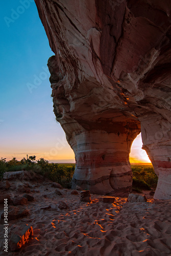 Sunset view through the rock, colorful arenite, contrasting with green vegetations and blue sky in Pedra furada tourist attraction, Jalapao, Brazil.