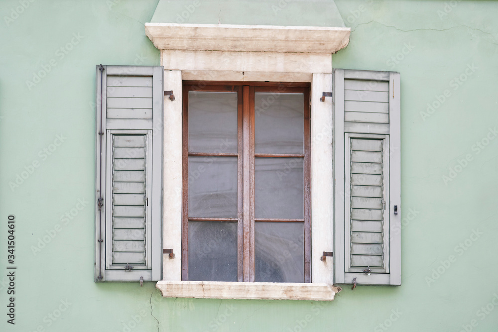Italian window on the green color wall facade with open wooden green shutters