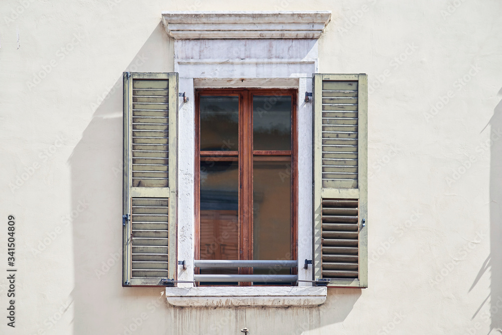 Fototapeta premium Italian window on the bright wall facade with open wooden shabby bright-green color shutters