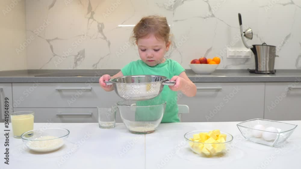 child sieving flour into a bowl. Kid is playing with a flour. child sieving flour into a bowl. Kid is playing with a flour.